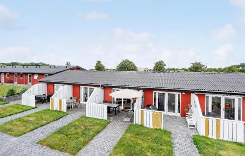 a red and white building with a patio and grass at Cozy Apartment In Aakirkeby With Wifi in Åkirkeby
