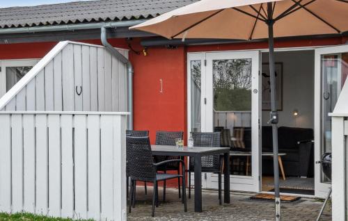 a table with chairs and an umbrella in front of a house at Cozy Apartment In Aakirkeby With Wifi in Åkirkeby