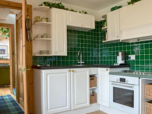 a kitchen with white cabinets and green tiles at Fearnmore Church in Fearnmore