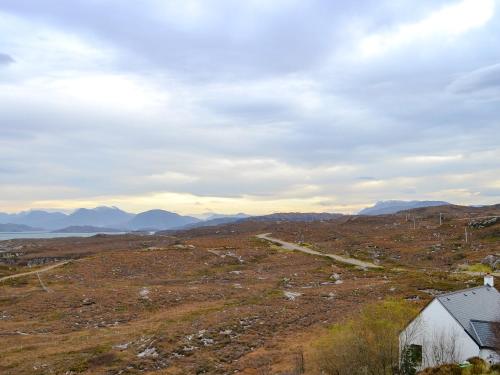 a view of a field with a barn and mountains at Fearnmore Church in Fearnmore