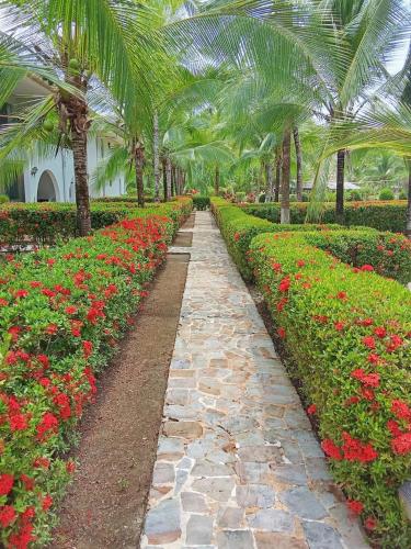 a pathway in a garden with flowers and palm trees at Modo relax Quepos in Quepos