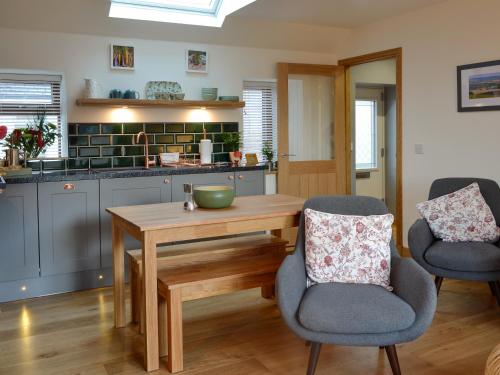 une cuisine avec une table en bois et deux chaises dans l'établissement Howe Cottage, à Laurencekirk
