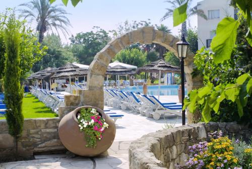 Una piscina con sillas y una maceta en un patio. en Basilica Holiday Resort, en Pafos