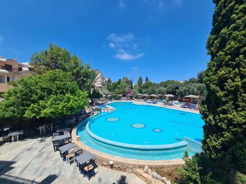 Una piscina en un complejo con sillas y árboles. en Basilica Holiday Resort, en Pafos