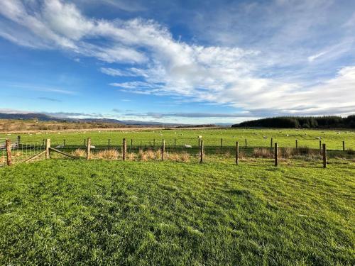 a fence in a field with sheep in the distance at Fiadh Ruadh-Uk40008 in Gartmore