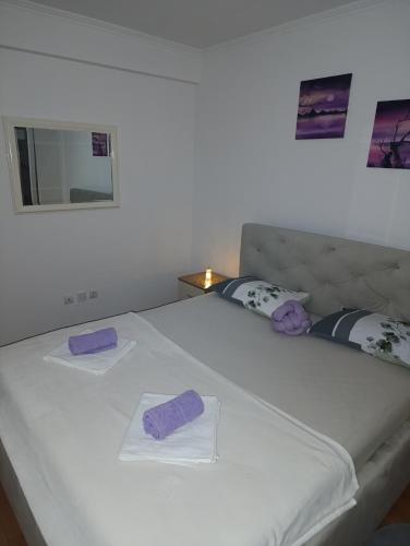 a white bed with two purple pillows on it at Apartman TEA Trebinje in Trebinje
