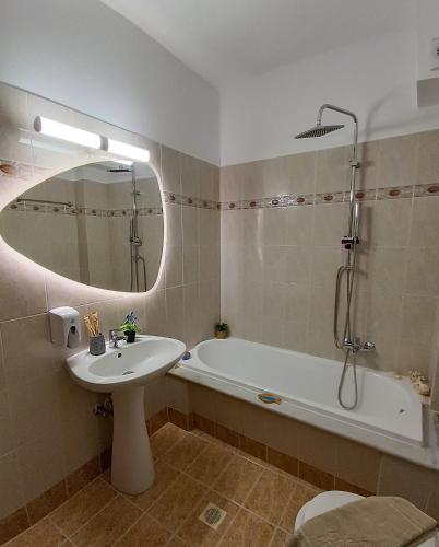 a bathroom with a sink and a tub and a mirror at Seaside Breeze Apartment in Sitia