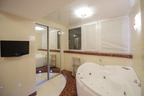 a bathroom with a bath tub and a tv in it at Апартаменты Петровские 80 кв м 2 комнатная в центре in Tomsk