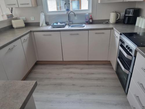 a kitchen with white cabinets and a sink at Lakeside Lodge in Dunbar
