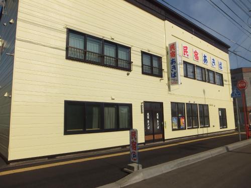 a white building with black windows on a street at Furano Minshuku Akiba in Furano
