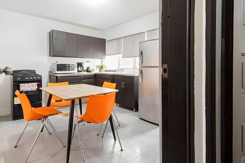 a kitchen with a wooden table and orange chairs at Casa Fundidora in Monterrey