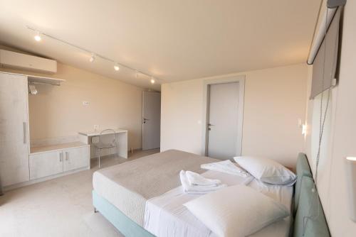 a white bedroom with a bed and a desk at Avali Deluxe Apartments in Lygia
