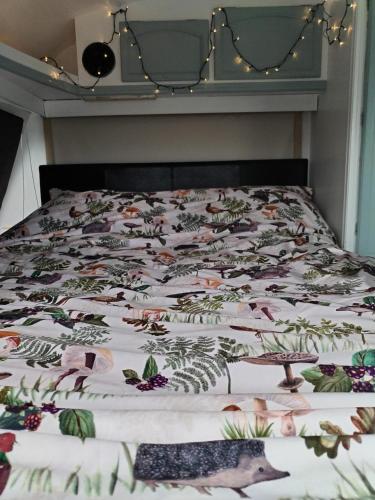 a bed with a quilt with animals on it at Cosy Caravan Walkers Ramblers Fishermen Cyclists in Abermule