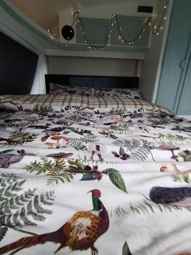 a bed with a blanket with birds on it at Cosy Caravan Walkers Ramblers Fishermen Cyclists in Abermule