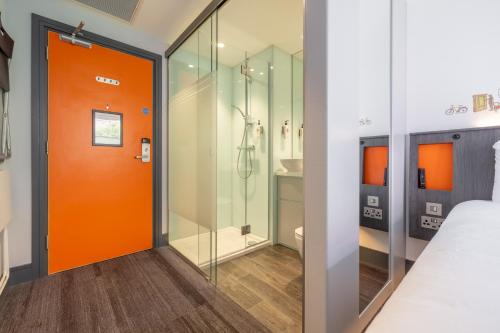 an orange door in a room with a shower at easyHotel Belfast in Belfast