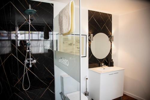 a bathroom with a mirror and a sink and a shower at Cristal apartamentos 1ºdireito Praça Velha in Angra do Heroísmo
