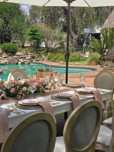 a table with chairs and glasses and a pool at Casa LaMich Garden Venue and Spa in Midrand