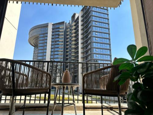 a balcony with two chairs and a table and a tall building at شقة فندقية بالشيخ زايد Zed residense in Cairo