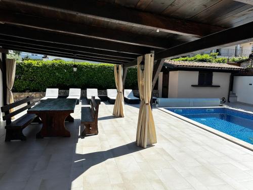 にあるPeaceful villa Terezaのプールサイドのパティオ(テーブル、ベンチ付)