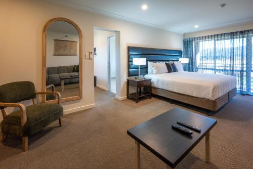 a hotel room with a bed and a chair and a table at Hanmer Springs Gateway Lodge in Hanmer Springs