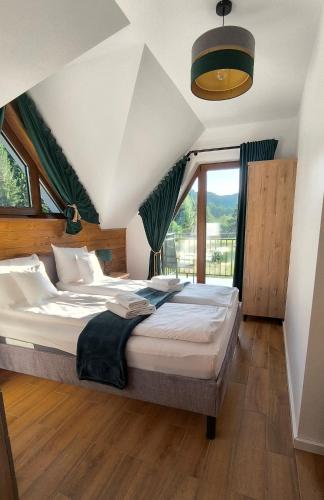a bedroom with a bed and a large window at Korona Pienin Domki & Apartamenty - Apartament z Sauna i grota solna in Szczawnica