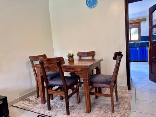 a dining room table with four chairs and a table at Green Haven Nsambya, Kampala in Nalakonge