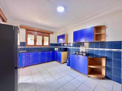 a blue kitchen with blue cabinets and tile floors at Green Haven Nsambya, Kampala in Nalakonge
