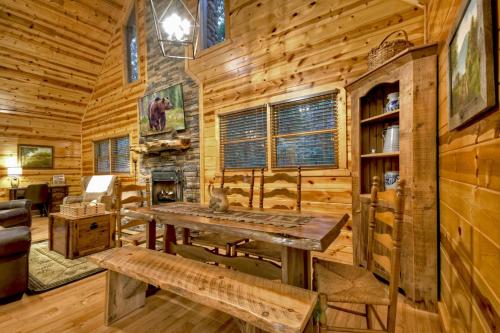 a log cabin with a table and a fireplace at A Little Bit of Heaven Swim in the creek soak in the hot tub and relax in comfort in Copperhill