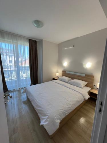 a bedroom with a large white bed and a window at Apartment D25 Pomorie in Pomorie