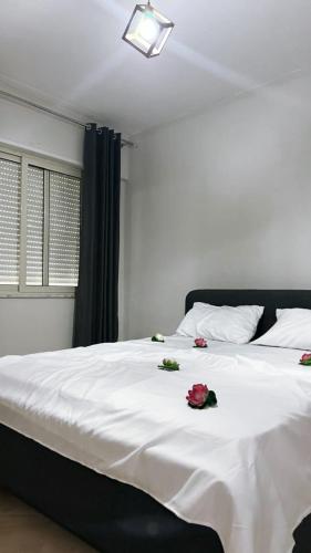 a bedroom with a white bed with roses on it at Leo apartaments with sea view in Durrës