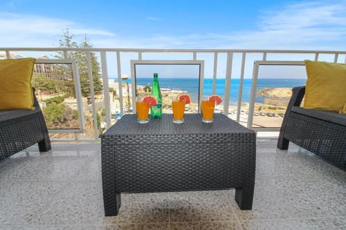 a table with three glasses and a bottle on a balcony at Seaview Escape I 60 seconds to the Beach in St. Julianʼs