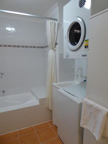 a white bathroom with a tub and a sink at Lifestyle Apartments at Ferntree in Fern Tree Gully
