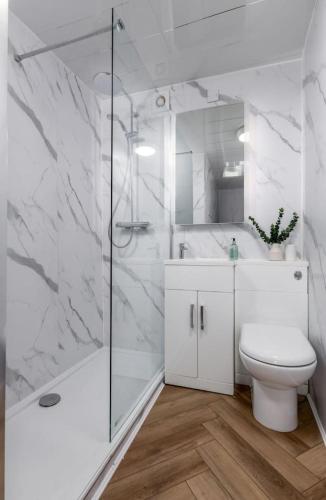 a white bathroom with a shower and a toilet at Modern Comfort in Historic Callander in Stirling