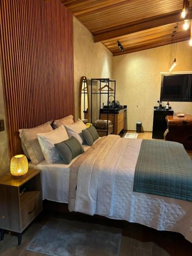a bedroom with a large bed and a television at Chalé Manacá in Sapucaí-Mirim