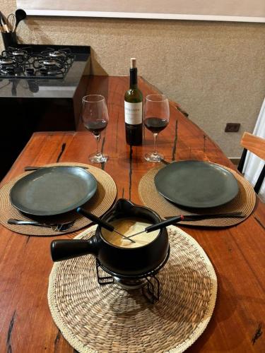 a table with two glasses of wine and a frying pan at Chalé Manacá in Sapucaí-Mirim