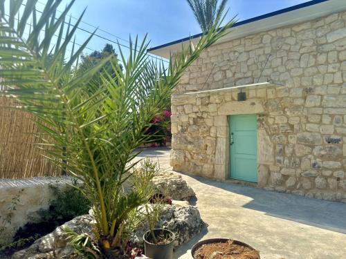 a stone building with a green door and a palm tree at Alma Del Monte Stone House w Pool Terrace 