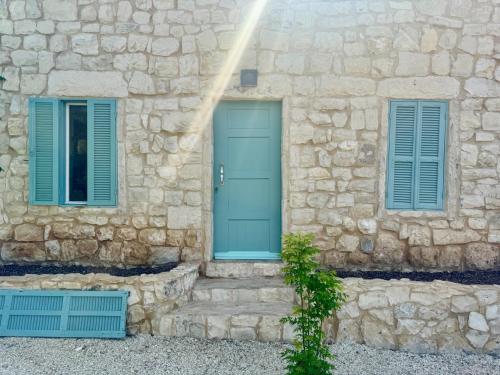a stone building with a blue door and two windows at Alma Del Monte Stone House w Pool Terrace 