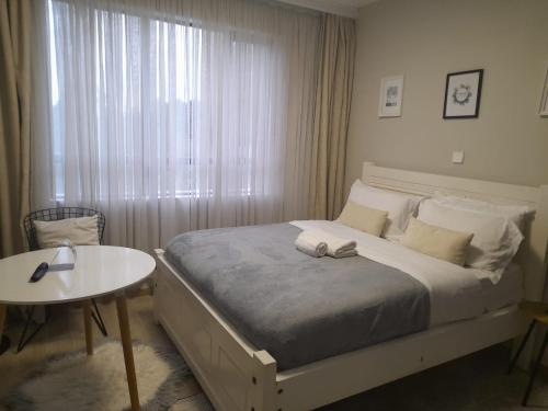 a bedroom with a bed and a table and a window at Hanover Studio Homes in Nairobi