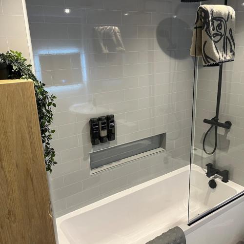 a shower with a glass door next to a bath tub at The Fishermans Rest in Castle Douglas