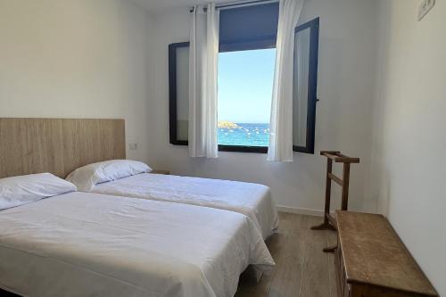 a bedroom with two beds and a window with the ocean at LETS HOLIDAYS Wake Up by the Sea in Victoria apartment 2 in Tossa de Mar