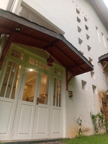 Una puerta de entrada de una casa blanca con toldo. en Ambuluwava Eco Resort, en Gampola
