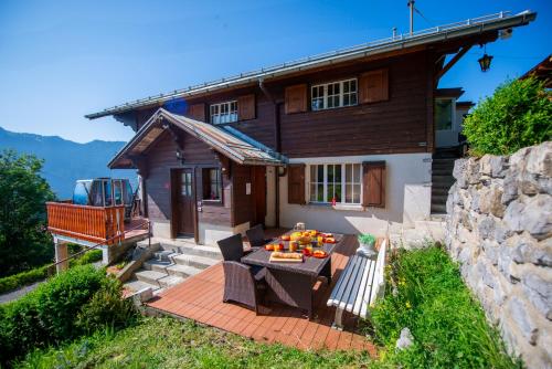 a house with a table and chairs on a patio at Chalet 6 personnes avec sauna in Leysin