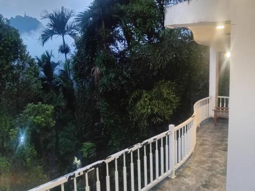 Un balcón de una casa con una valla y árboles en Ambuluwava Eco Resort, en Gampola