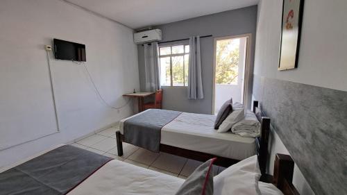 a room with two beds and a tv and a window at Hotel Nobrega - São Paulo - Aeroporto Congonhas in Sao Paulo