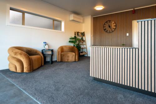 a room with two chairs and a clock on the wall at Hanmer Springs Gateway Lodge in Hanmer Springs