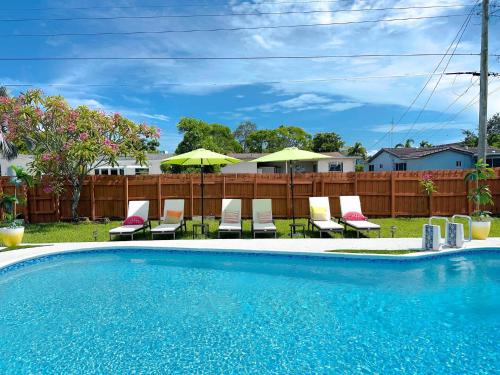 Una piscina con sillas y sombrillas en un patio. en Modern Family Pool Home Near Beach Vibes, en Hollywood