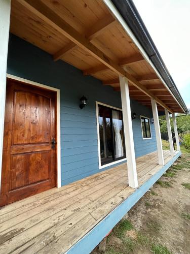a front porch of a house with a wooden door at Blue Cabaña - La Herradura in Quellón