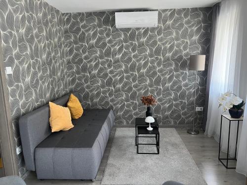 a living room with a gray couch and a patterned wall at Sophia Apartman Gödöllő in Gödöllő