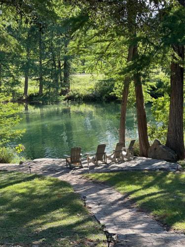 a group of benches sitting next to a lake at Sanctuary on the Frio in Concan