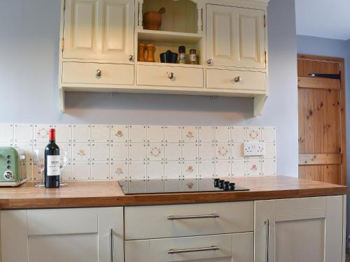 a kitchen with white cabinets and a bottle of wine at The Gig House in Stonham Aspall